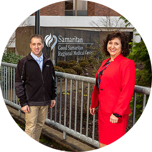 two healthcare executives standing in front of a hospital.
